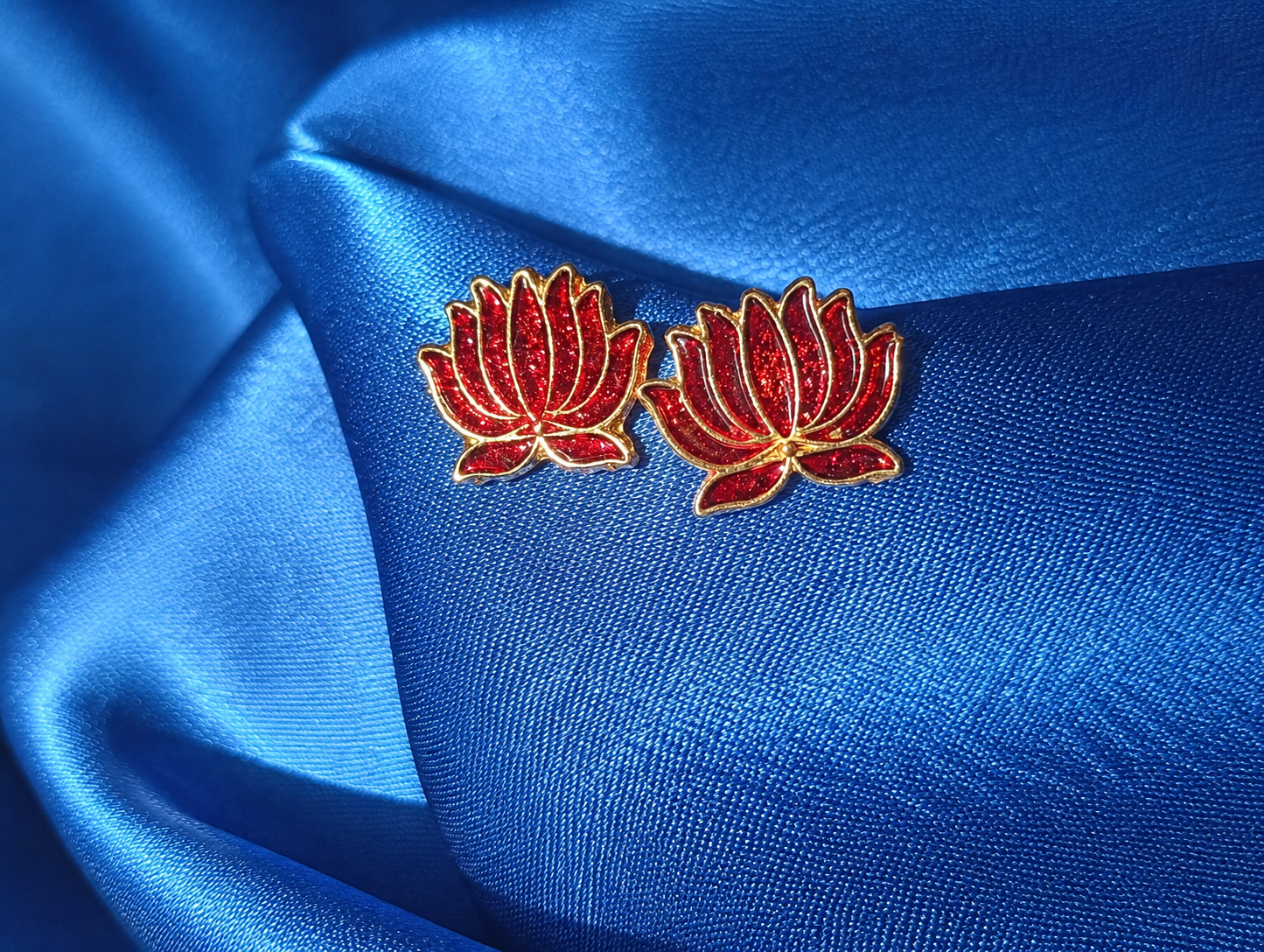 Maroon floral earrings on a blue satin background