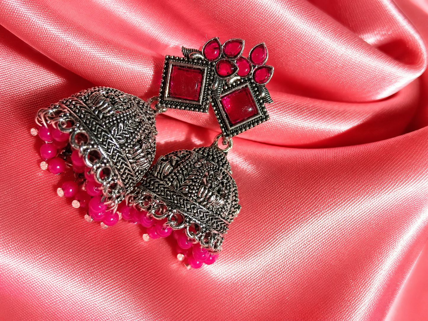 Decorative brooch with red gemstones and pink beads on a pink fabric background