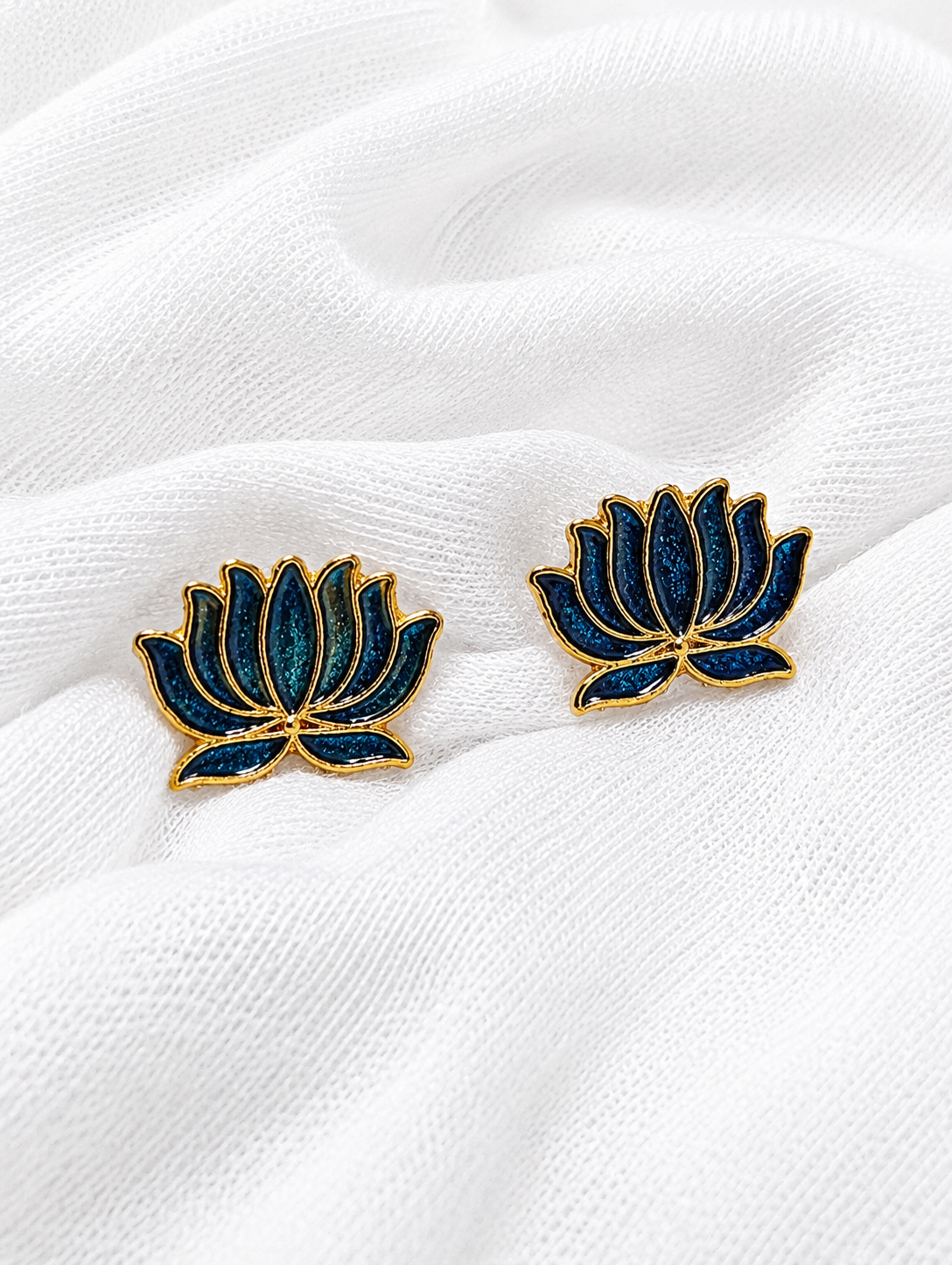 Blue lotus flower earrings on a white fabric background