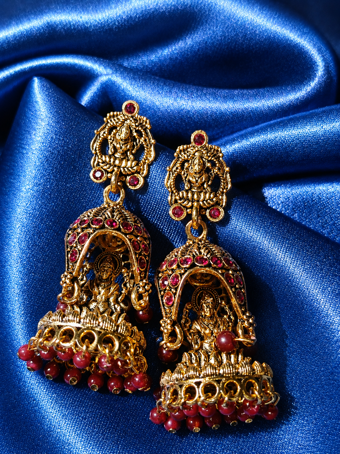 Gold and red earrings on blue satin fabric
