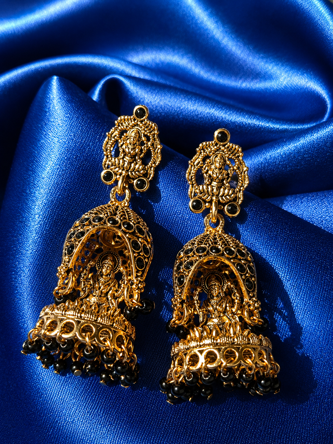 Gold earrings with intricate designs on a blue satin background