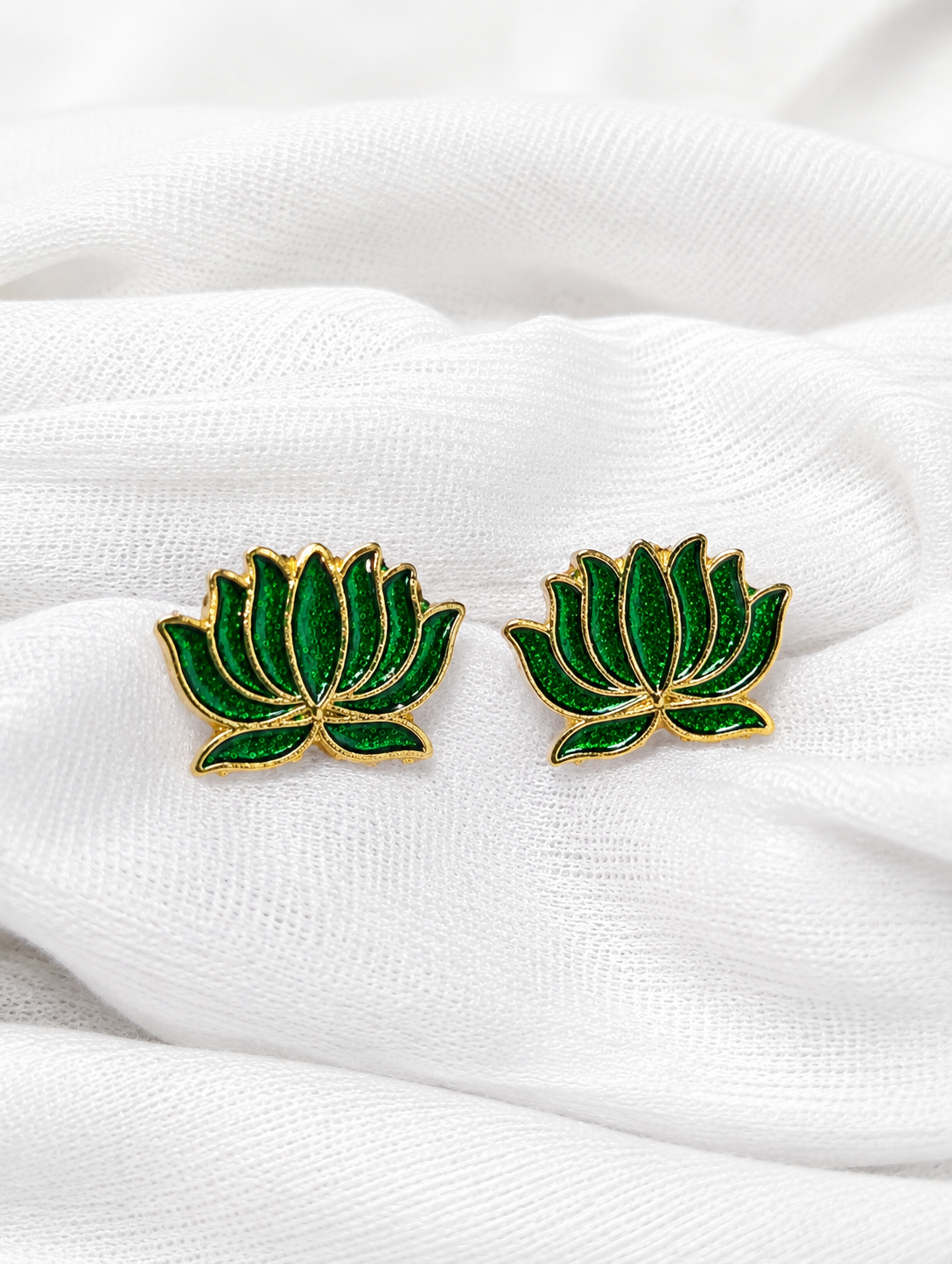 Green lotus flower earrings on a white fabric background