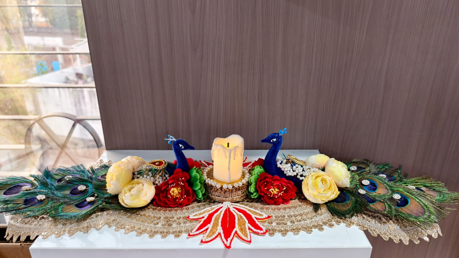 Handmade peacock candle centerpiece with blue peacock figurines, LED candle, real peacock feathers and fabric roses on gold lace runner