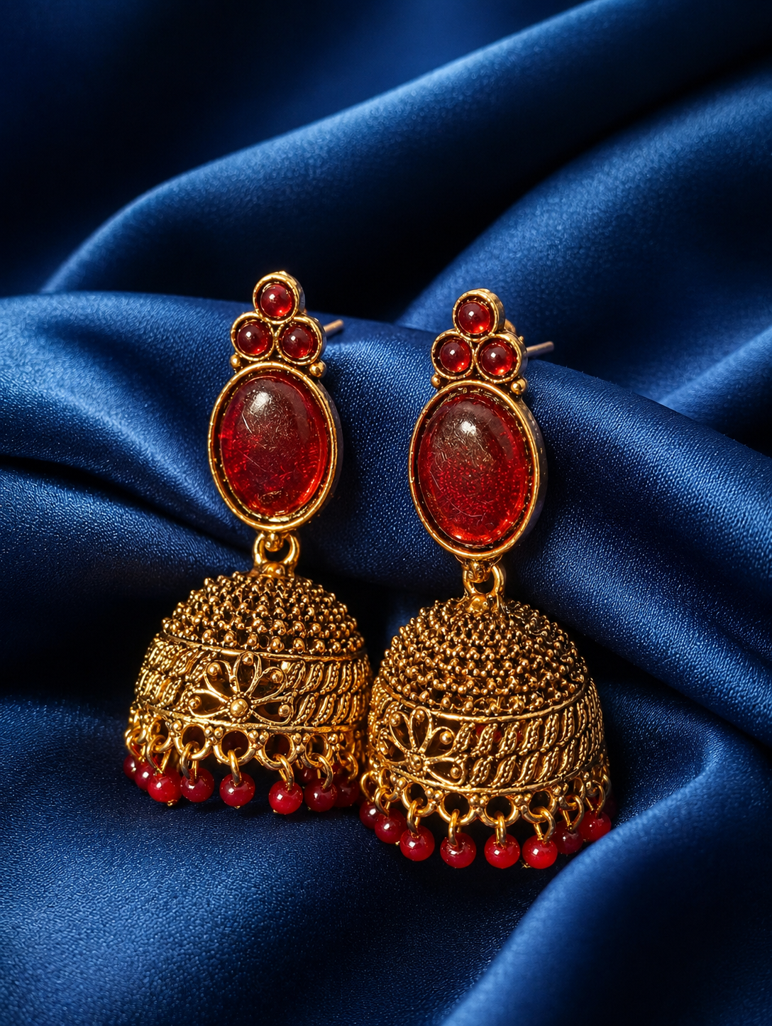 Gold and Maroon earrings on a blue satin background
