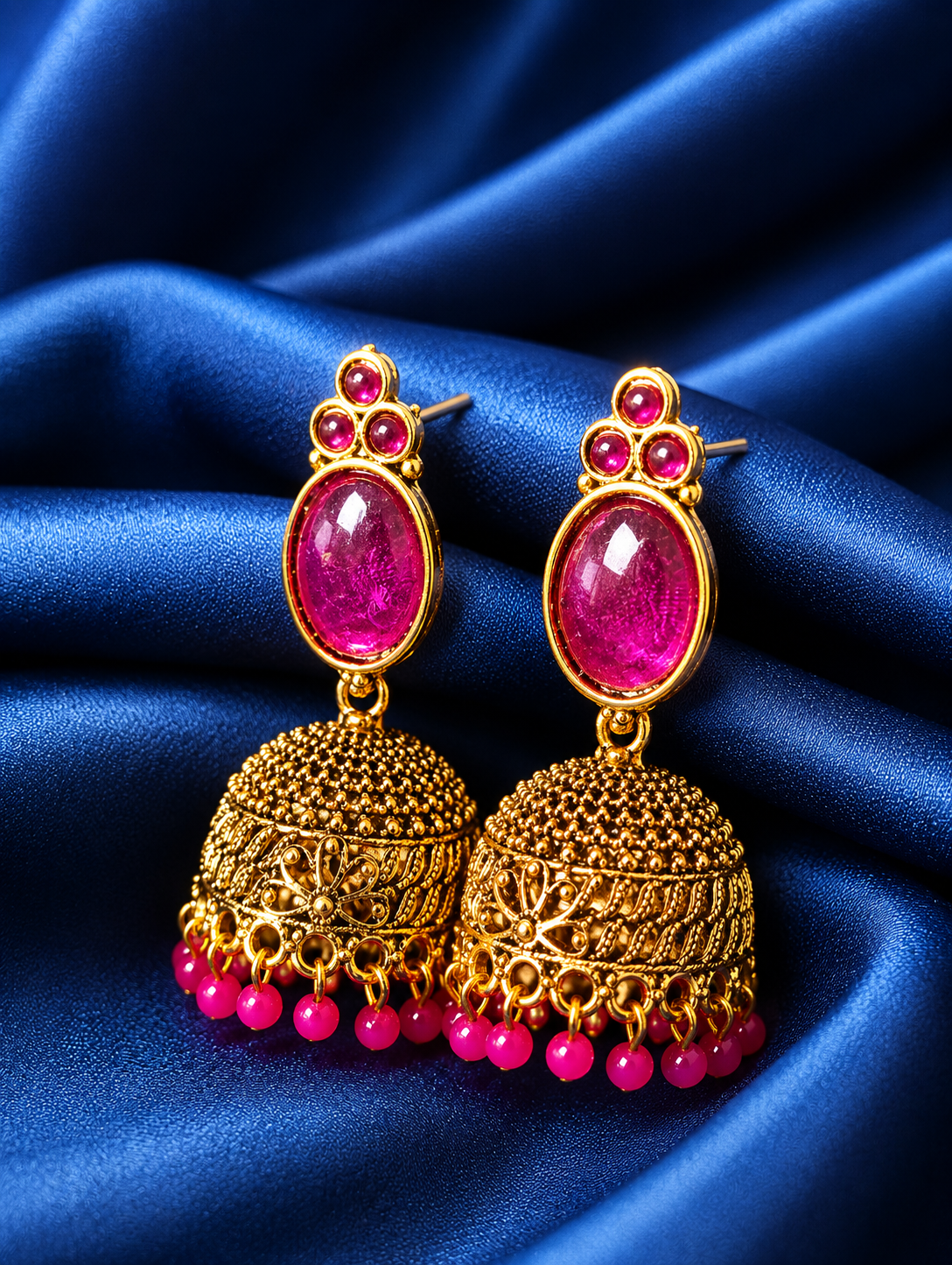 Gold and pink earrings on a blue satin background
