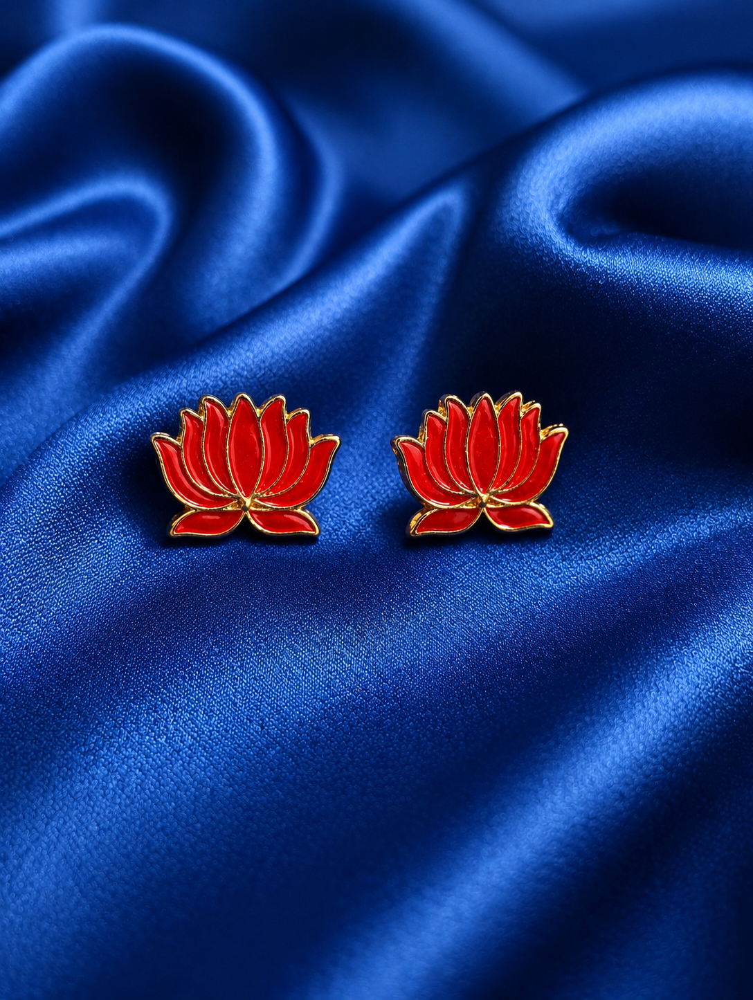 Red flower-shaped earrings on blue satin fabric