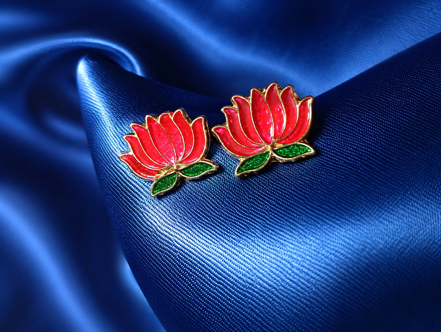 Pink flower-shaped earrings on blue satin fabric